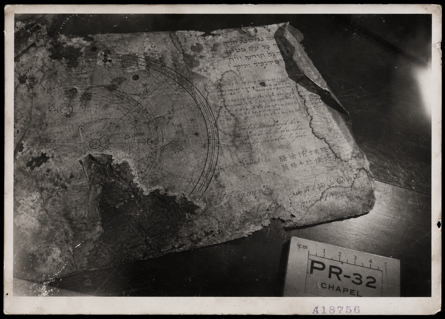Poor-condition 1930s black-and-white photograph of a damaged manuscript page with a partial circular diagram.